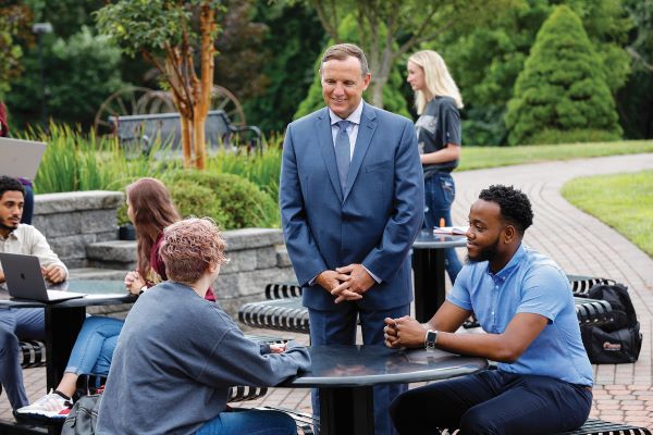 Ken Daly talking with students on campus