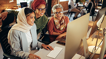 Three businesswomen looking at a computer monitor