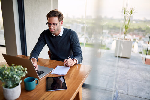 Salarié sur assis à une table face à son ordinateur recherchant quels sont les dispositifs pour se former