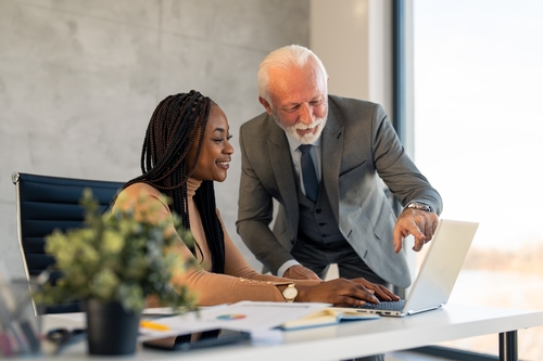 A senior businessman and a younger colleague looking at a laptop