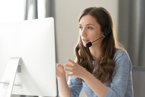 A female manager in a headset talking on the phone while looking at her computer screen