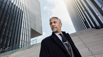 A businessman standing with buildings in the background